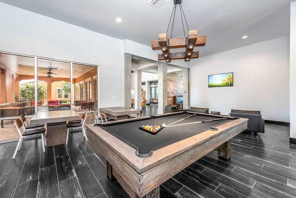 a pool table in the clubhouse of a home with a bar and a dining area