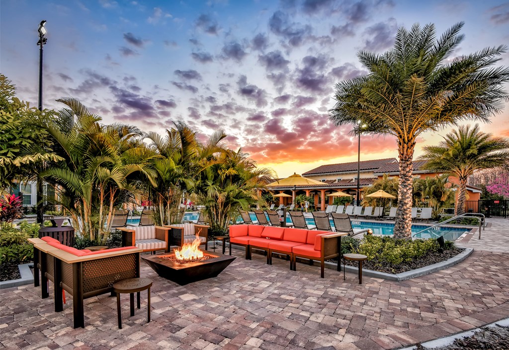 a swimming pool with palm trees and a patio with a fire pit