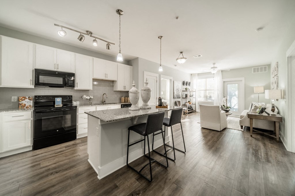 an open kitchen and living room with a marble counter top