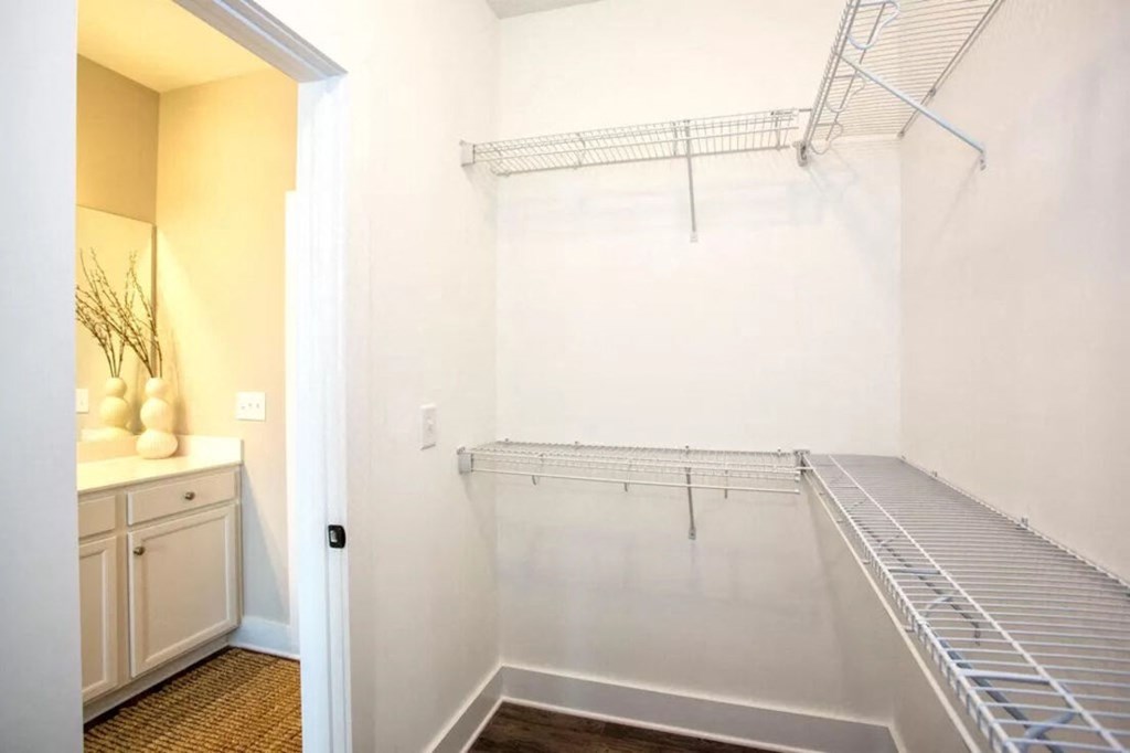 a walk in closet with white walls and a mirrored closet door