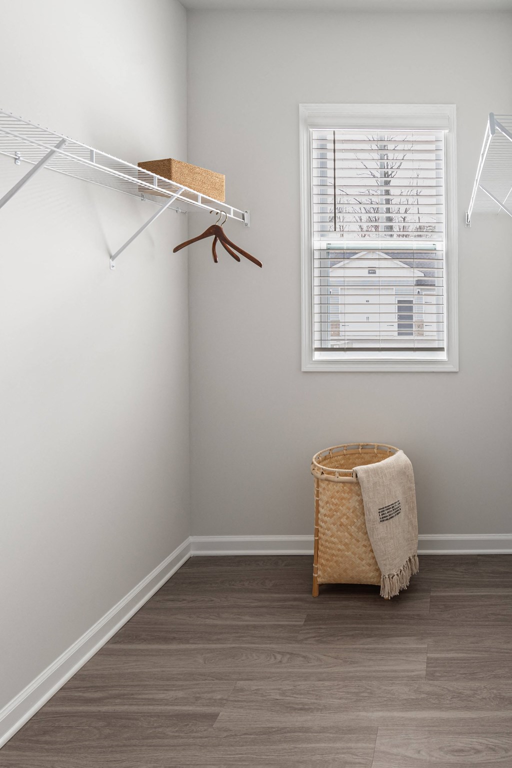 a walk in closet with a window and a basket and a clothes rack