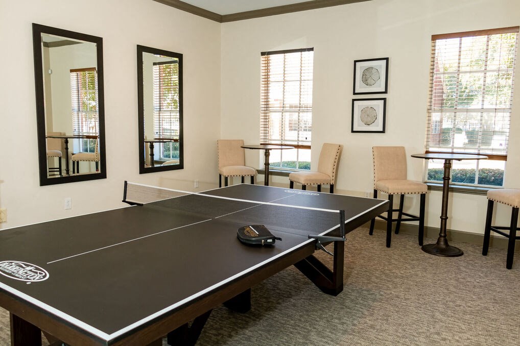 a games room with a ping pong table and chairs