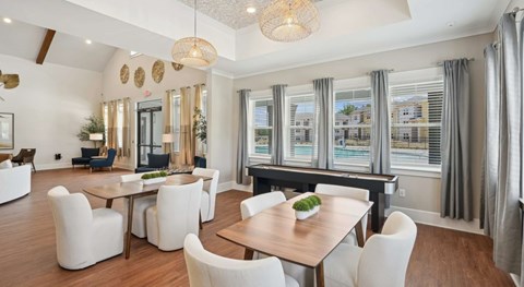 A dining room with a wooden table surrounded by white chairs.