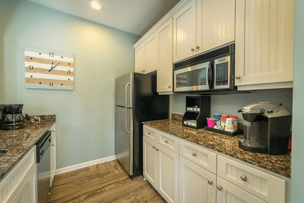 a kitchen with white cabinets and a black refrigerator