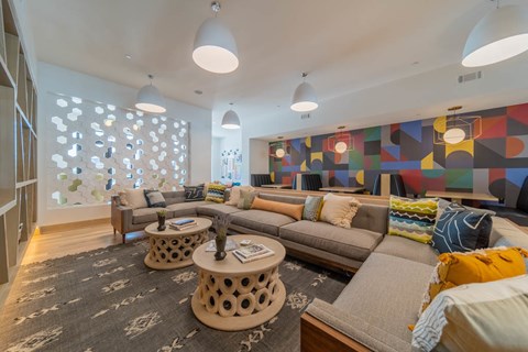A living room with a grey couch and a large painting on the wall.