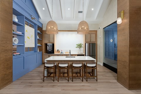 A modern clubhouse kitchen with a dining table and chairs at Evolve Holly Ridge Apartments in Holly Ridge, NC.