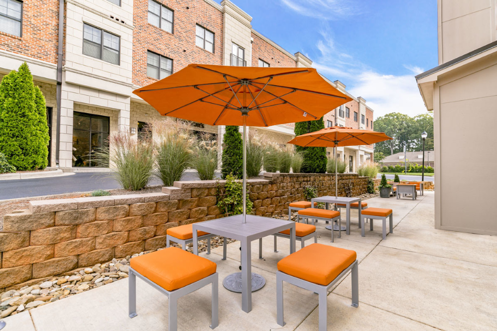 a patio with orange umbrellas and tables outside of a building
