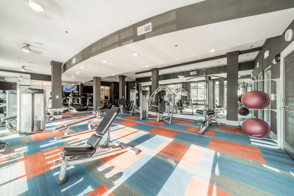 a gym with a colorful floor with exercise machines and a red ball