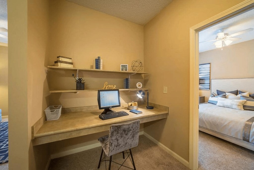 a bedroom with a desk with a computer and a bed
