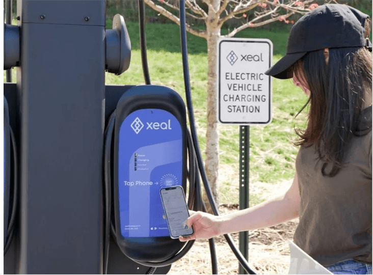 a woman using her cell phone at an electric vehicle charging station