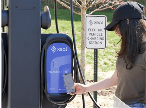 a woman using her cell phone at an electric vehicle charging station