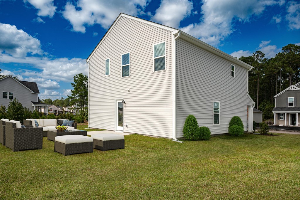 a white house with a yard with couches and chairs