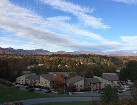 A large building complex with a parking lot in front of it at River Ridge Apartments in Asheville, NC