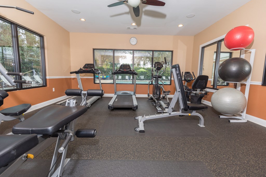 the gym has plenty of exercise equipment and a large window
