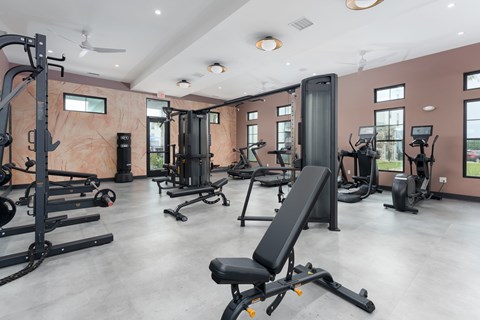 A gym with a variety of equipment including treadmills, weights, and exercise machines at Evolve Holly Ridge Apartments in Holly Ridge, NC.