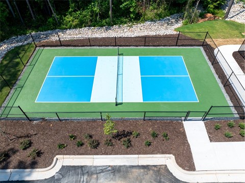 A tennis court surrounded by a black fence and a white border.