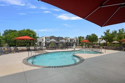 A large outdoor swimming pool with a red umbrella.