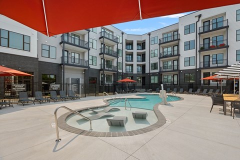 A large outdoor pool area with a red canopy and lounge chairs.