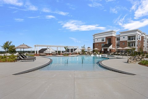 A large swimming pool in front of a building with a white fence around it.