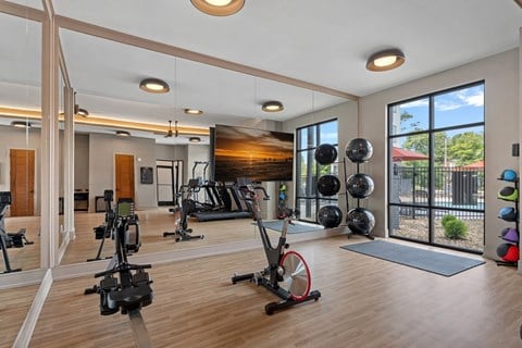 A gym with a variety of exercise equipment including treadmills, stationary bikes, and weightlifting equipment.