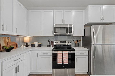 A kitchen with white cabinets and a stainless steel refrigerator.