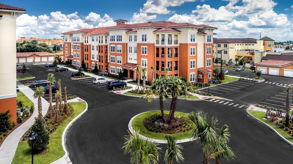 an aerial view of an apartment complex with a parking lot and palm trees