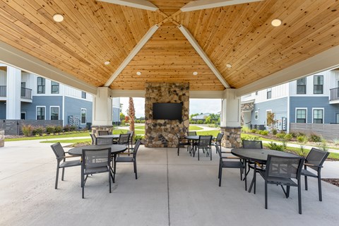 A patio with a stone fireplace and chairs at Evolve Holly Ridge Apartments in Holly Ridge, NC.