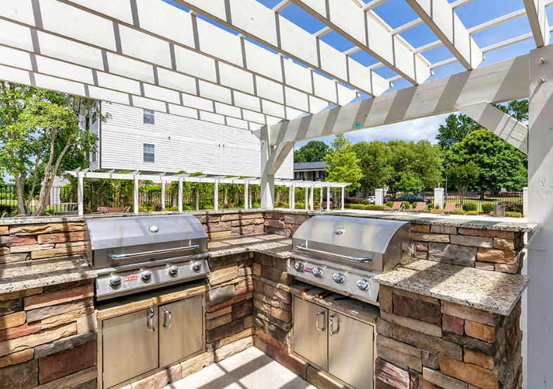 the outdoor kitchen has two stainless steel appliances and a pergola