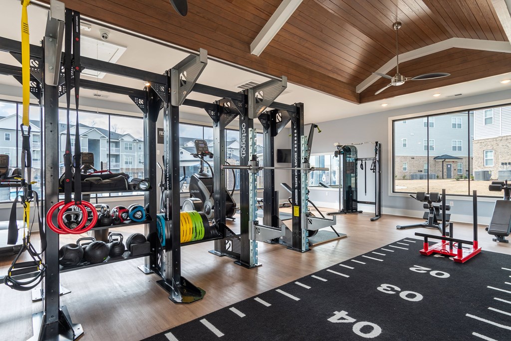 a home gym with weights and cardio equipment and a large window