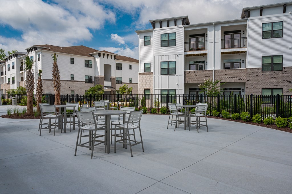 A patio with chairs and a table in front of apartment buildings.