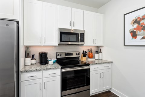 A kitchen with white cabinets and a black stove top oven.