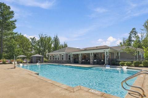 A large swimming pool with a slide and a house in the background.