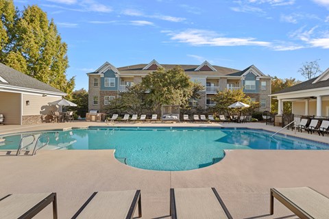 A large swimming pool in front of a building with a blue sky in the background.