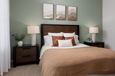 A bedroom with a large bed and two nightstands with lamps.