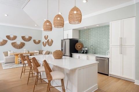 A kitchen with a white counter and wooden chairs.