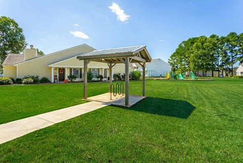 A playground with a swing set and a pavilion in the background.
