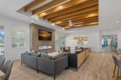 A modern living room with a grey sofa and a wooden ceiling.