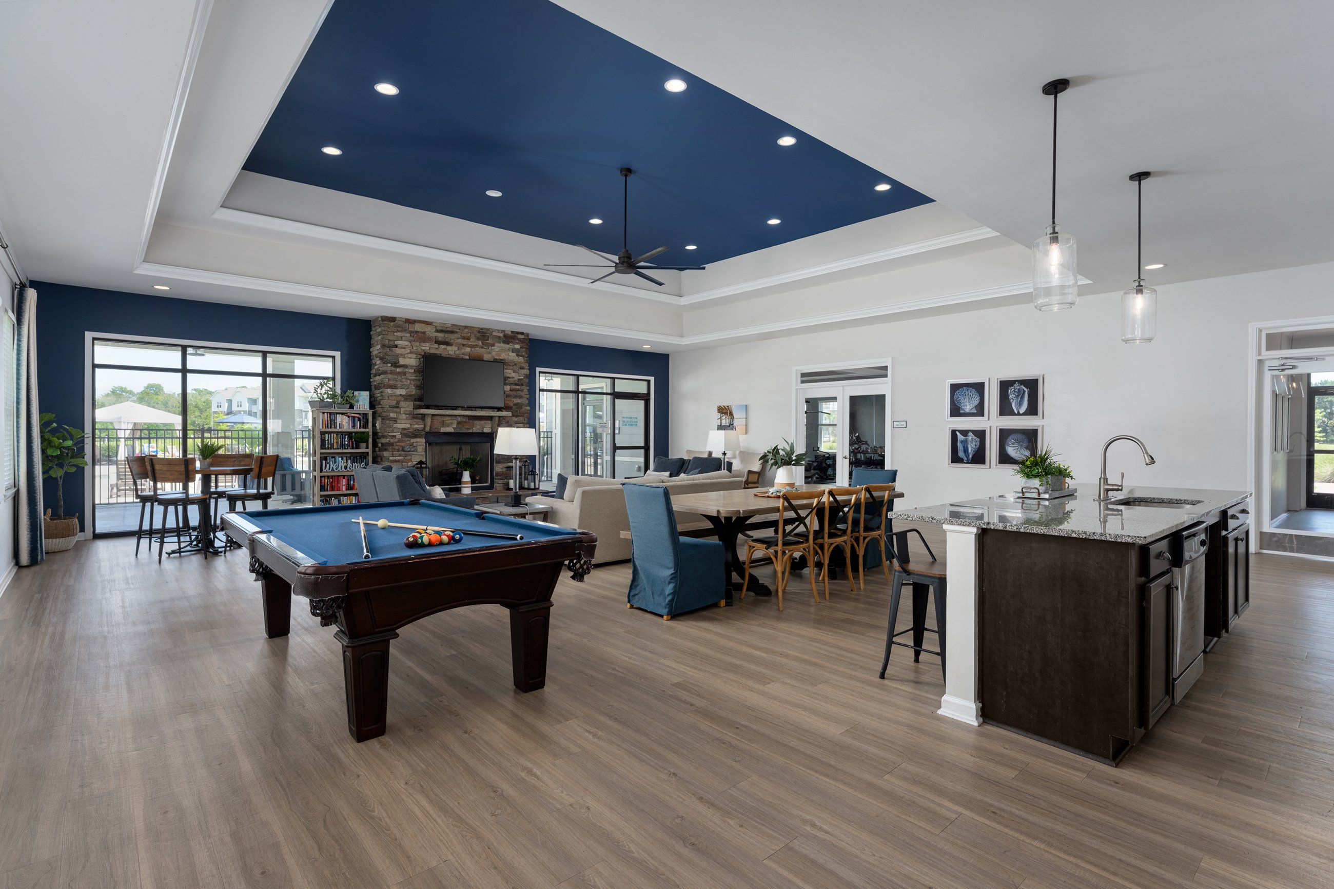 A large room with a pool table and a kitchen area.