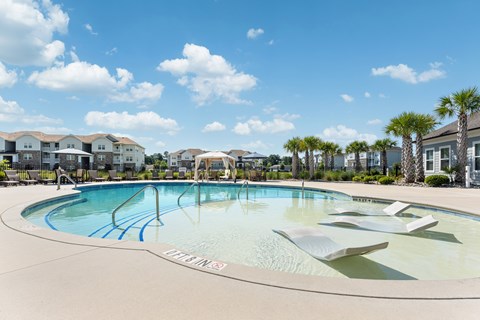 A pool with a slide and a sun lounger.