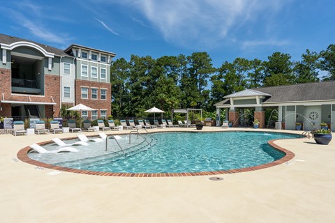 A large swimming pool surrounded by lounge chairs and umbrellas.