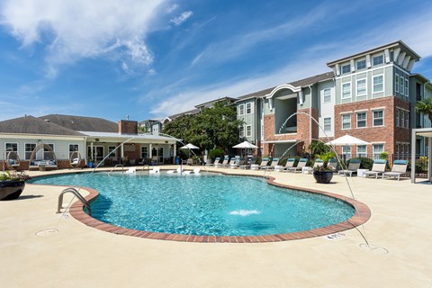 A large swimming pool in front of a building with a patio area.