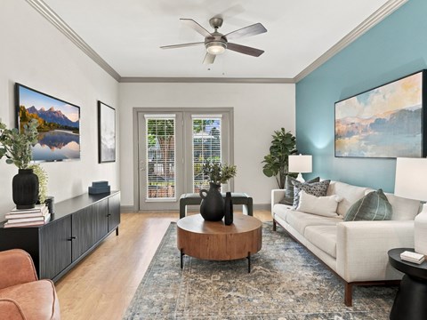A living room with a ceiling fan, a sofa, a coffee table, and a painting on the wall.