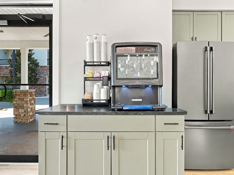 A kitchen with a refrigerator, a microwave, and a counter with a stone pillar.