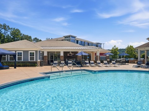 A large swimming pool in front of a building with a blue sky above.