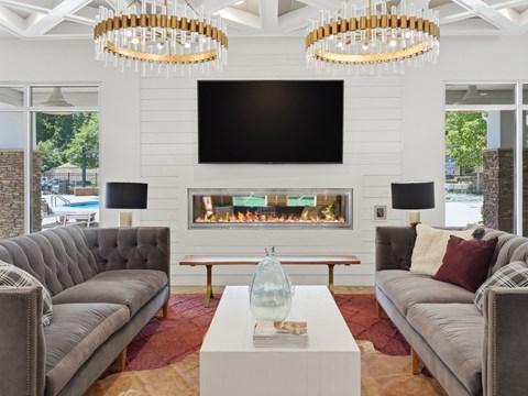 A modern living room with a grey sofa, a white coffee table, and a fireplace.
