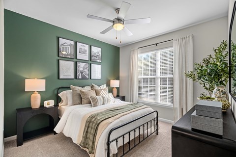 A bedroom with a bed, nightstand, and a ceiling fan.