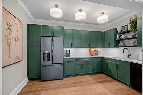 A kitchen with green cabinets and a fridge.