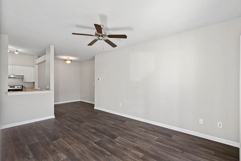 A room with a ceiling fan and wooden flooring.