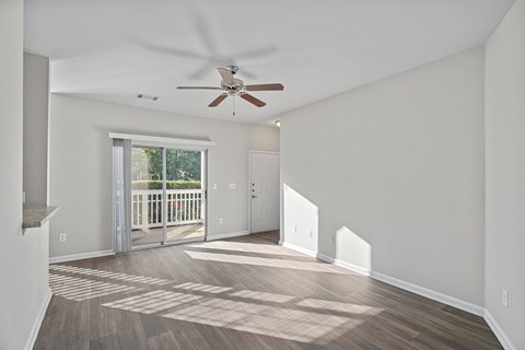 A room with a ceiling fan and a sliding glass door leading to a balcony.