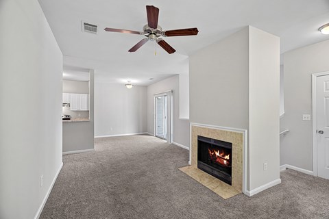 A living room with a fireplace and a ceiling fan.